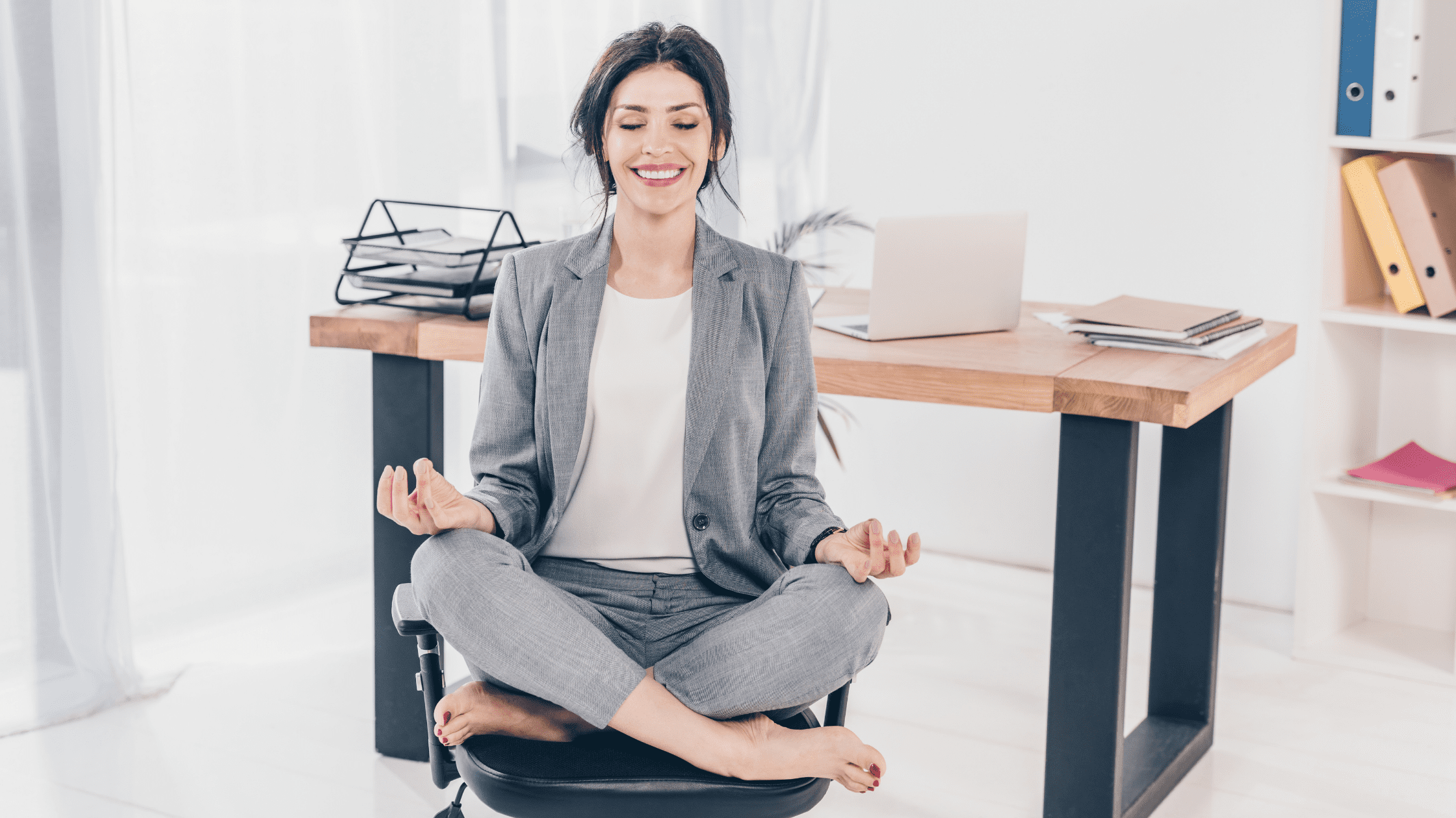 Happy energetic businessman practises yoga positions while working on  laptop computer. Funny fit flexible young man in suit and glasses doing  bridge pose on studio floor while using modern notebook PC Photos